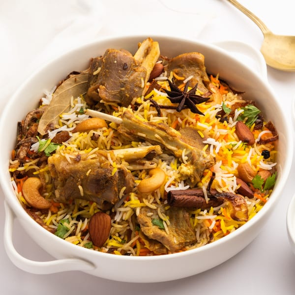 A close-up of Desi Flavors' Indian lamb biryani, garnished with nuts, spices, and herbs.